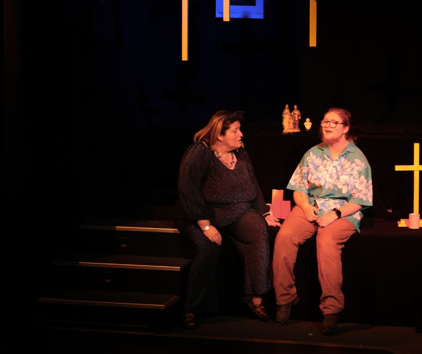 Amanda Sutherland as Ruth sitting beside Elliot Howe as Len on a raised stage platform during a rooftop scene in The Banana Bender.